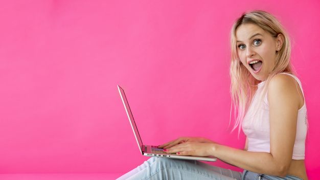 happy smiling girl on laptop in front of a pink background